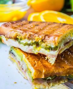 two halves of a sandwich sitting on top of a cutting board next to lemons