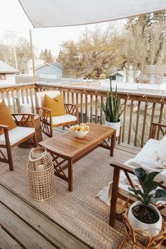 a wooden deck with chairs and tables on top of it next to a potted plant