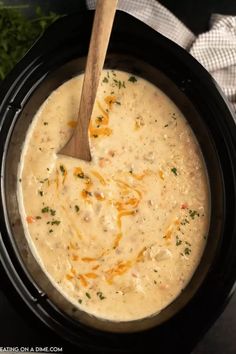 a wooden spoon is in a crock pot filled with chicken and cheese soup, ready to be eaten