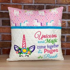 a pillow with unicorns and magic on it sitting next to a brick wall that says, come together in the pages of a book