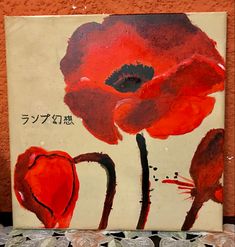 a red flower painted on a canvas next to some silver coins and an orange wall