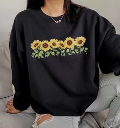 Sunflower Crewneck Sweatshirt, Sunflower lover shirt, Gift for Gardener, Gardening Shirt, Spring flowers, Kindness Shirt, Sunflowers Plants Sizes: S-5X Unisex Fit Size up for an oversized sweatshirt fit DTG Print Machine wash inside out and fry on low heat.  T Shirts and Tank Tops Available  Made with a unisex heavy blend crewneck sweatshirt is pure comfort. These sweaters are made from polyester and cotton. This combination helps designs come out looking fresh and beautiful. The collar is ribbe Spring Long Sleeve Top With Sunflower Print, Long Sleeve Sunflower Print Tops For Spring, Spring Long Sleeve Sunflower Print Top, Yellow Long Sleeve Tops With Sunflower Print, Yellow Long Sleeve Top With Sunflower Print, Black Floral Print Sweatshirt For Spring, Casual Black Floral Print Sweatshirt, Fall Crew Neck Top With Sunflower Print, Relaxed Fit Crew Neck Top With Sunflower Design