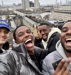 four men are taking a selfie on top of a building in london, england