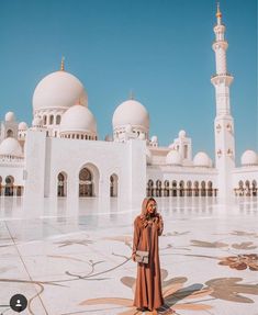 a woman standing in front of a white building with many arches and domes on it