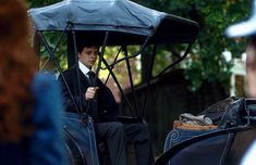 a man riding in the back of a buggy with an umbrella over his head