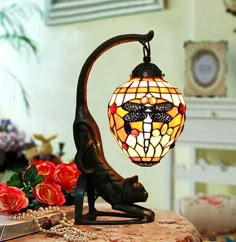 a lamp that is sitting on top of a table next to some flowers and books