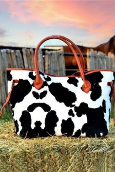 This fun fuzzy fabric bag will send you over the moon! Black and white cow print puts a western twist on this trendy tote. Cognac vinyl detailing, metal feet, and magnetic button top closure. Cognac nylon inner lining and zipper pocket. 22'' W x 14' H x 3'' D Rectangular Cow Print Travel Bag, Black Bag With Cow Print For Everyday Use, Trendy Cow Print Bags For Everyday Use, Casual Everyday Bag With Cow Print, Casual Cow Print Bags For Daily Use, Cow Print Purse, Moon Black And White, Black And White Cow Print, Printed Leather Bag