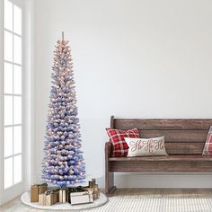 a blue christmas tree sitting next to a wooden bench in a room with white walls