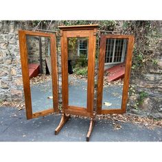 an old wooden folding mirror on wheels in front of a brick wall and stone building