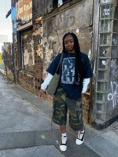 a woman standing in front of a building with graffiti on it