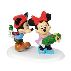 two mickey mouse figurines are holding a christmas tree and giving each other a present