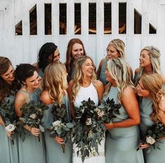 a group of women standing next to each other in front of a white fence with flowers