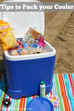 a cooler sitting on top of a beach next to a blue container filled with food