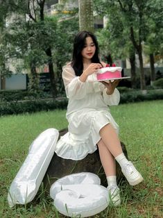 a woman sitting on top of a rock holding a piece of cake in her hand