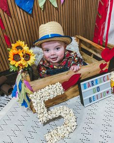 a baby in a wooden crate with sunflowers on the table next to it