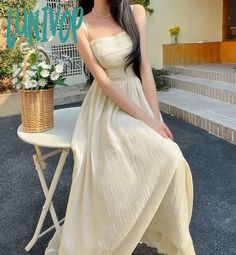 a woman sitting on top of a white chair next to a flower pot with flowers in it