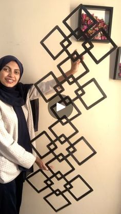 a woman standing next to a wall with some pictures on it