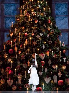 a woman standing in front of a christmas tree