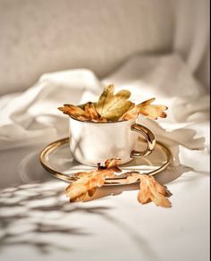 a white cup filled with leaves on top of a table