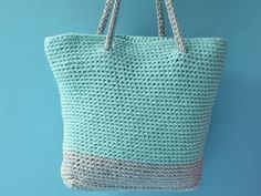 a crocheted tote bag hanging from a hook on a blue wall,