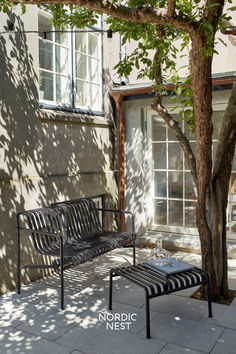 a bench sitting next to a tree in front of a building on a sunny day