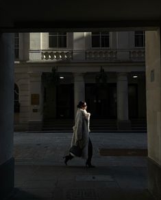 a woman is walking down the street at night