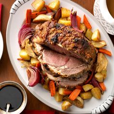 a white plate topped with meat and veggies next to a cup of coffee