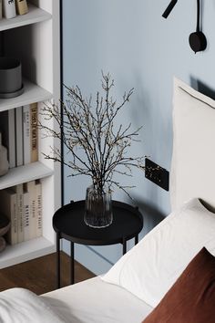 a bedroom with a bed, table and bookshelf in the corner next to it