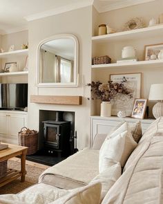 a living room filled with furniture and a fire place under a mirror on the wall