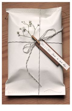 a wrapped gift with a tag tied to it on a wooden table next to a piece of string