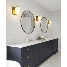 a bathroom with two sinks and three mirrors on the wall above them is white tile flooring