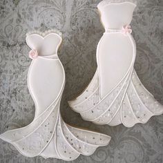 two decorated cookies in the shape of wedding gowns on a gray tablecloth background