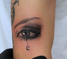 a woman's leg with a tattoo on it and a tear coming out of her eye