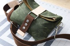 a green bag sitting on top of a table next to a pair of metal scissors