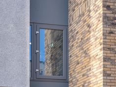 a window on the side of a building that has a brick wall and grey trim