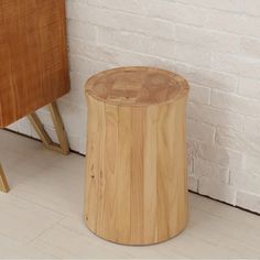 a wooden stool next to a white brick wall and wood flooring on the ground