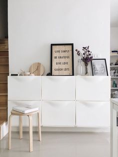 there is a white cabinet with some pictures on it and a chair next to it