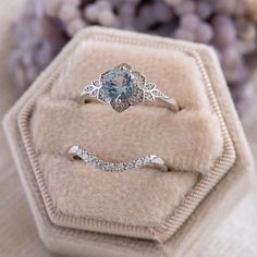 an engagement ring with a blue topazte surrounded by diamonds in a velvet box