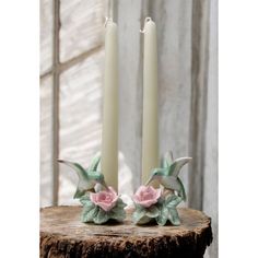 two white candles with pink flowers on them