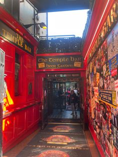 the inside of a restaurant with red walls and posters on the outside wall as well as people walking through it