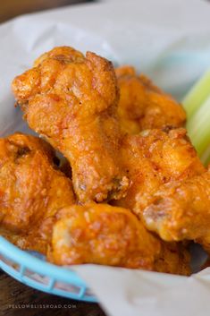 crispy baked chicken wings with celery in a blue bowl on a wooden table