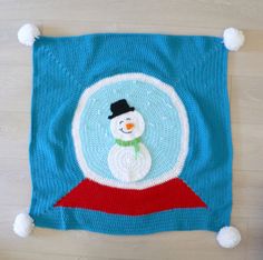 a knitted snowman on top of a blue blanket