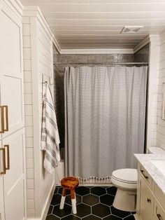 a bathroom with black and white tile flooring next to a toilet, sink and shower curtain