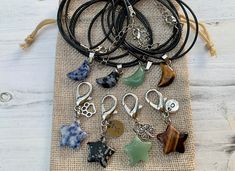 a bunch of necklaces that are on a piece of burlap cloth with some charms hanging from them