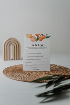 an orange card sitting on top of a wicker place mat next to a plant