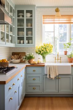 a kitchen with blue cabinets and yellow flowers on the window sill above the sink