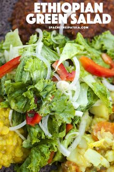 a salad with lettuce, tomatoes and other vegetables on it is shown in the foreground