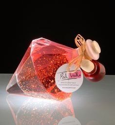 a bottle of red liquid sitting on top of a white table next to a black background