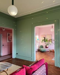 a living room with green walls and pink couches