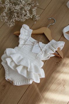 a white knitted romper and shoes on the floor